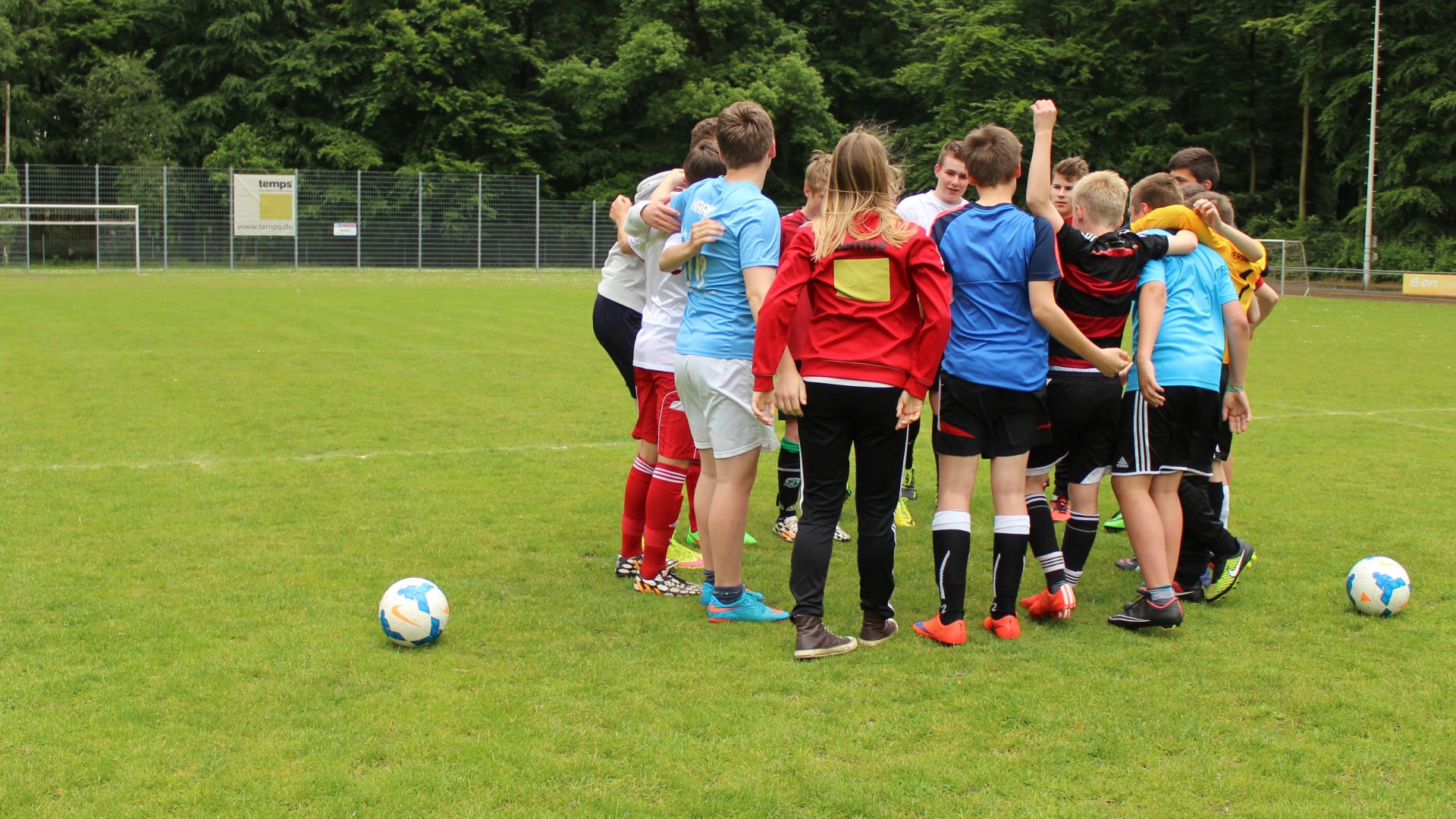 Mädchen und Jungen stehen auf dem Fußballfeld als gemischtes Team