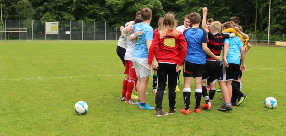 Mädchen und Jungen stehen auf dem Fußballfeld als gemischtes Team