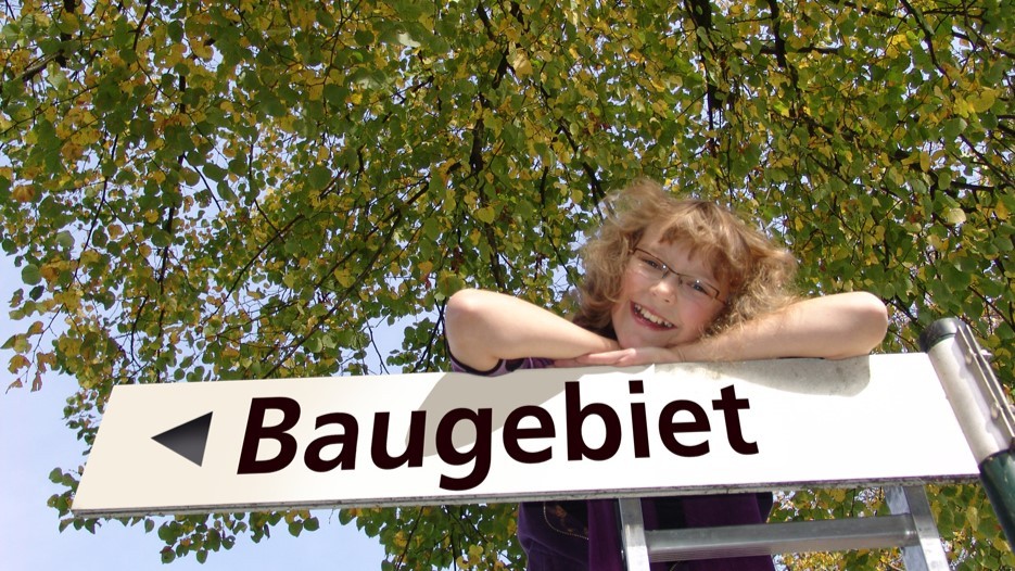 Mädchen lehnt auf dem Hinweisschild Baugebiet