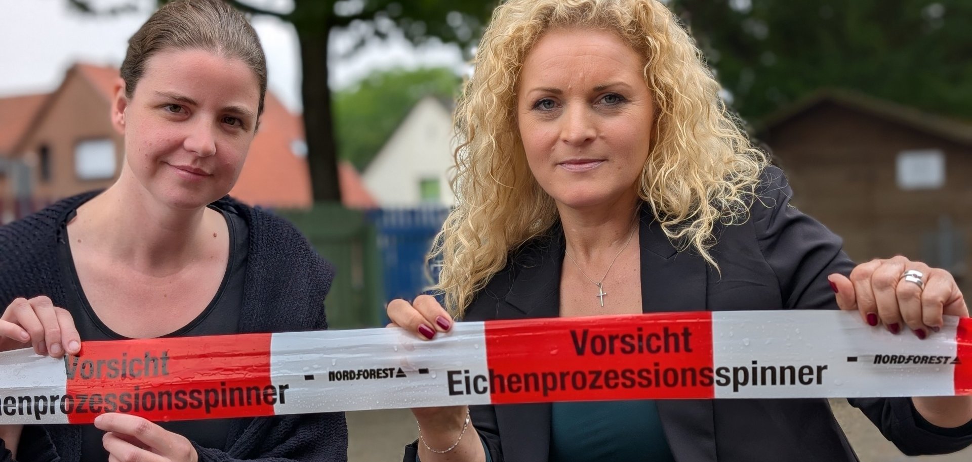 Maren Vennes und Judy Grothe vor dem Absperrband, das vor dem Eichenprozessionsspinner warnt
