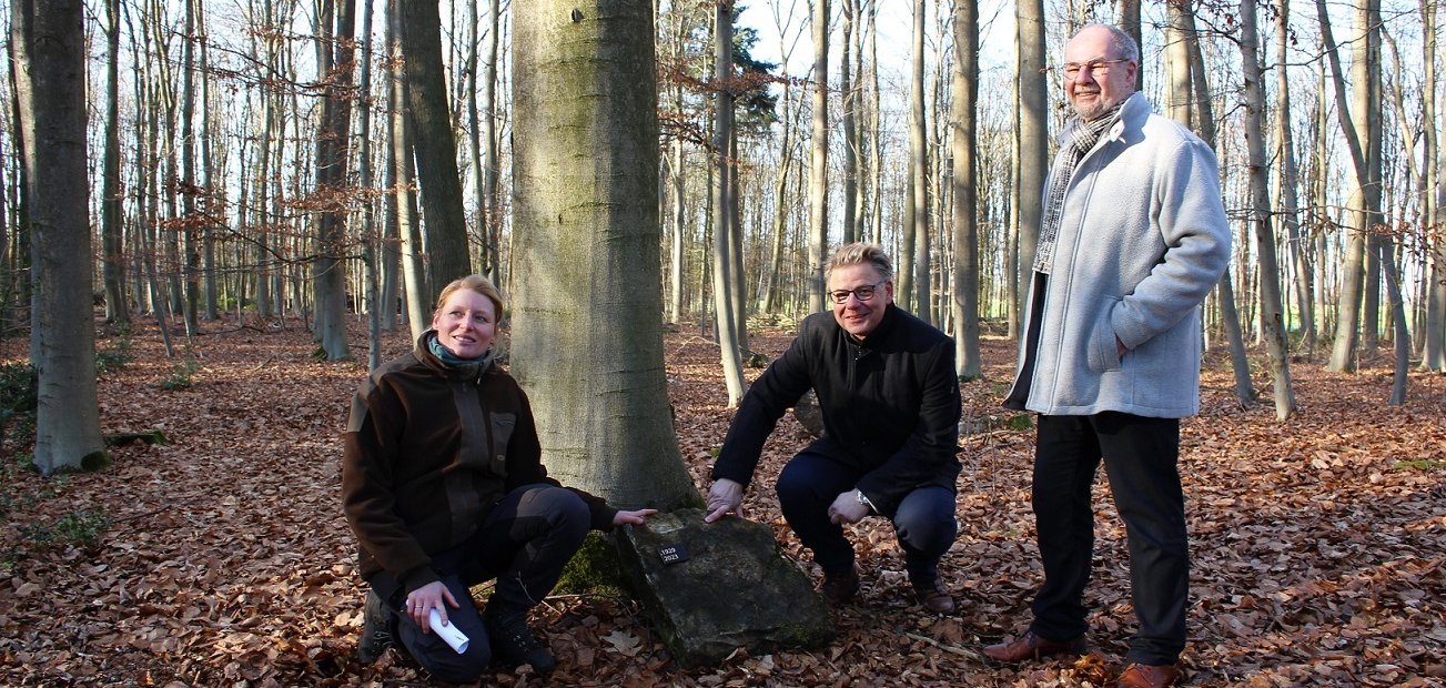 Der Wald, ein Baum, ein Stein und eine Namensplakette: Imke Beck demonstriert gemeinsam mit Martin Franke (Mitte) und Arend de Vries, wie die Grabstätten im Waldfriedhof am Rosenbraken gekennzeichnet werden sollen