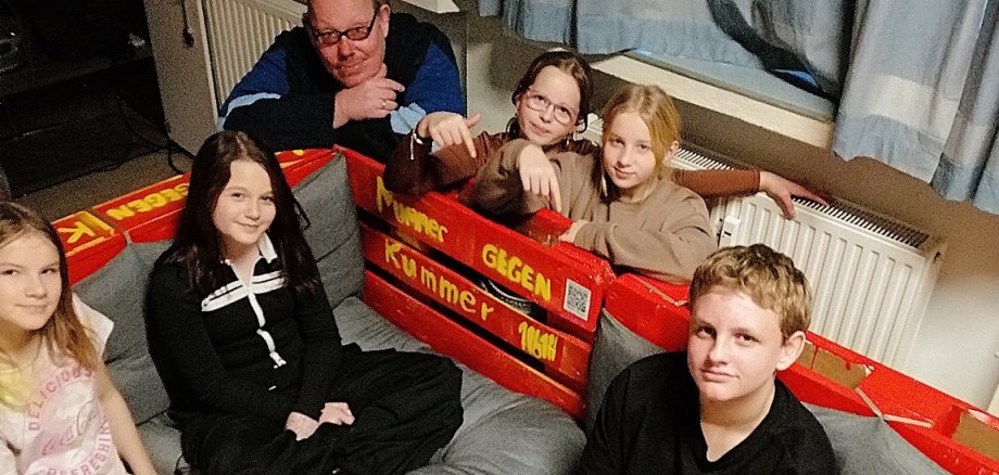 Kinder und Jugendliche sitzen auf der selbst gestalteten Bank