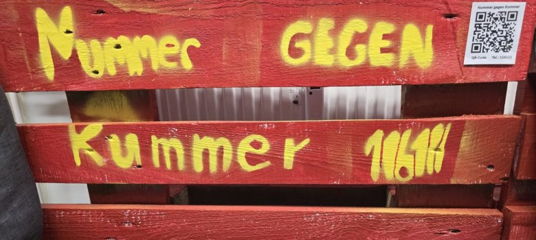 auf der roten Eckbank stehen die Worte Nummer gegen Kummer und ein QR Code