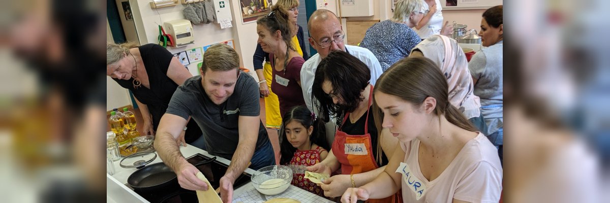 Gemeinsam Kochen Fröhliche Menschen von Jung bis Alt aus unterschiedlichen Herkunftsländern kochen gemeinsam nach internationalen Rezepten.