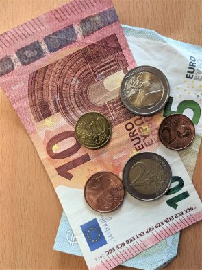 Ein 10 Euro und ein 5 Euroschein liegen zusammen mit Münzgeld auf einem Tisch.
