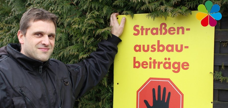 Andreas Wagener mit einem Plakat gegen Straßenausbaubeiträge