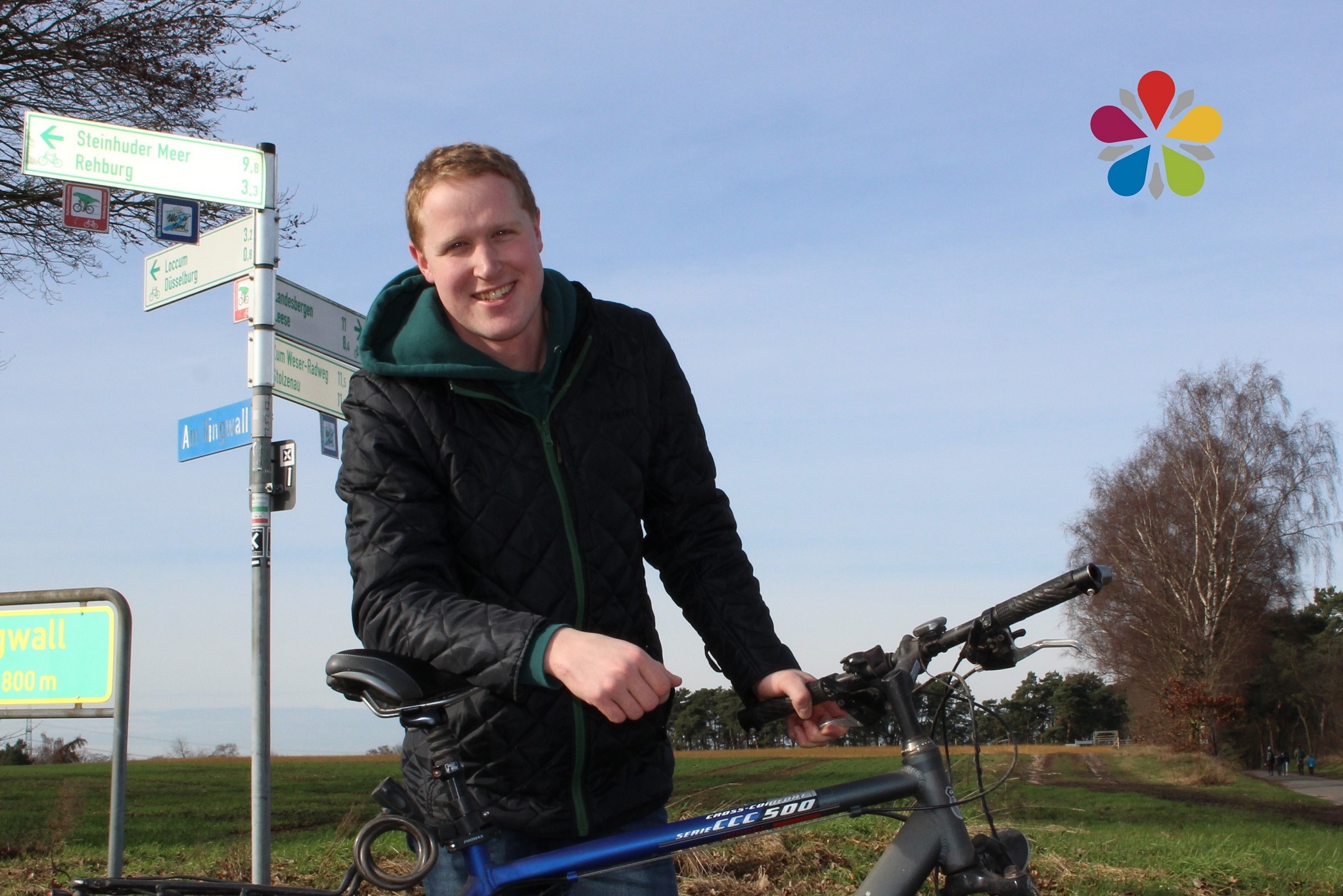 Julian Voigt lehnend auf einem blauen Fahrrad