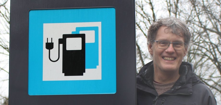 Ratsherr Markus Richter mit einem Hinweisschild auf eine E-Ladestation