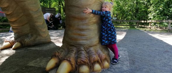Kind umarmt ein Bein eines Dinos