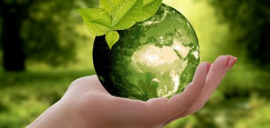 Eine Hand hält einen Apfel, der als grüne Erde abgebildet ist.