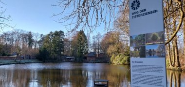 Blick auf einen Teich mit dem Hinweisschild auf das Cisterscapes Projekt